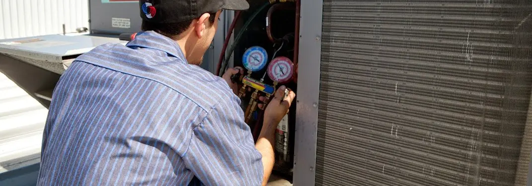 HVAC technician servicing a condenser unit in EspaÃ±ola
