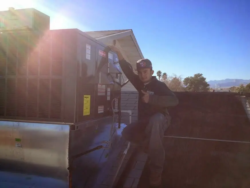 HVAC technician performing Heat Pump Repair on a rooftop unit in EspaÃ±ola